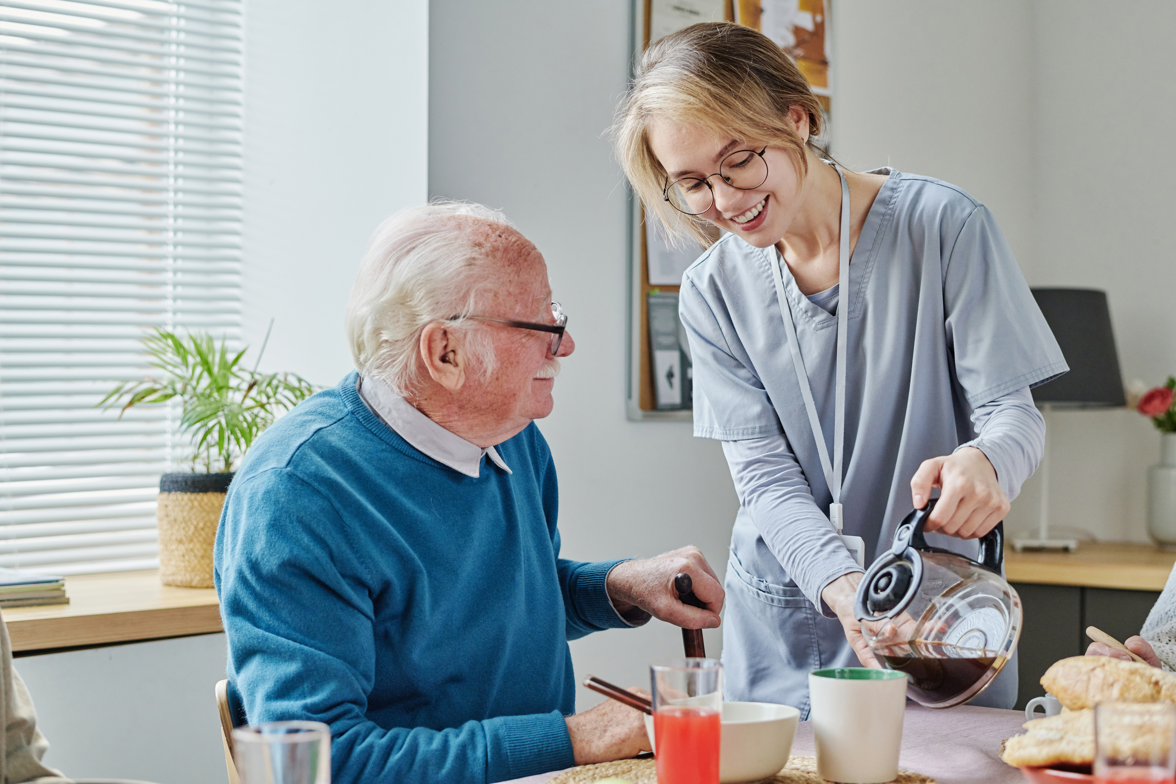 Pflegerin schenkt alten Mann Kaffee ein